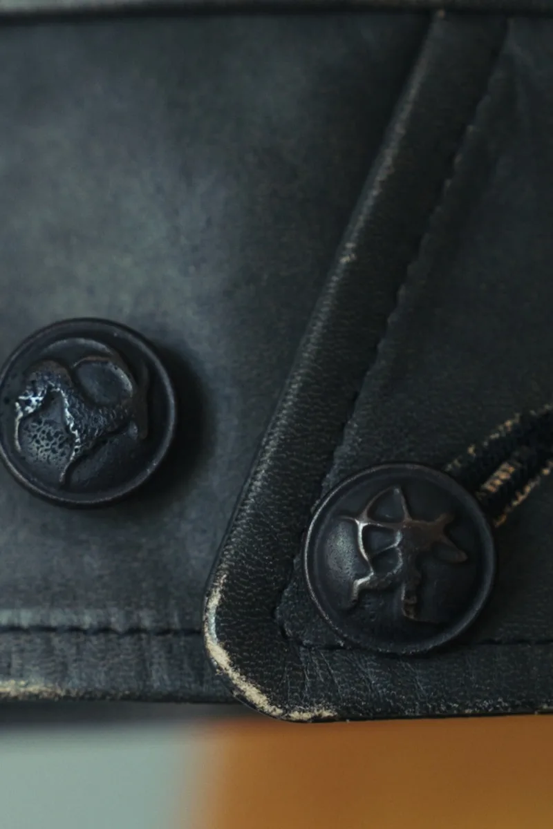 Gros plan sur des boutons en cuir noir avec motifs gravés.