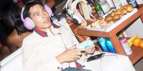 Personne avec casque et manette, plateau de hamburgers sur table.