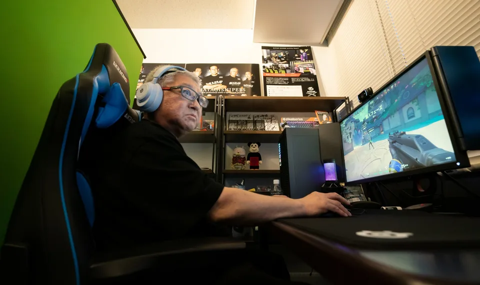Homme avec casque joue à un jeu vidéo sur un écran d'ordinateur.