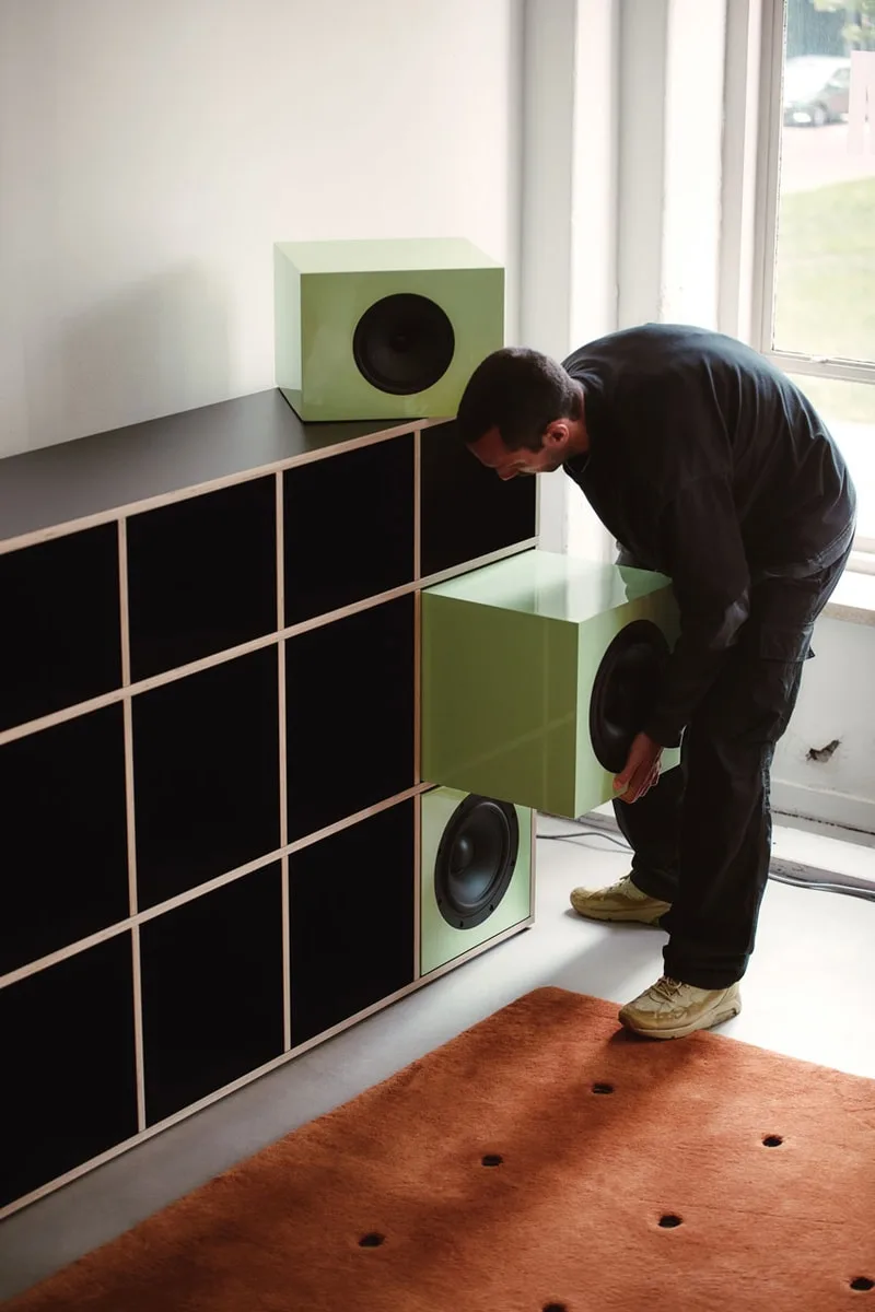Homme ajustant des haut-parleurs dans une étagère design moderne.