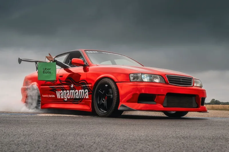 Voiture de course rouge avec logo Wagamama et sac Uber Eats.