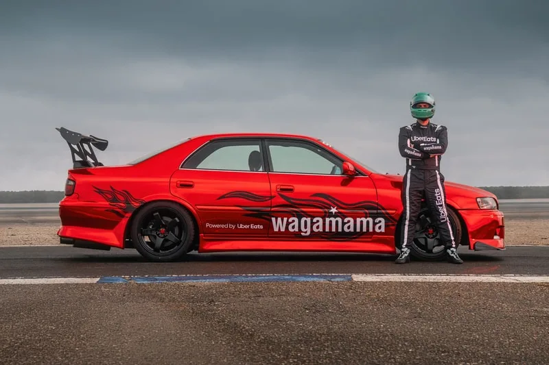 Voiture de course rouge avec flamme et motard en combinaison.