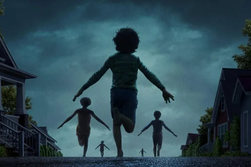 Des enfants courent dans une rue sombre vers la lumière.