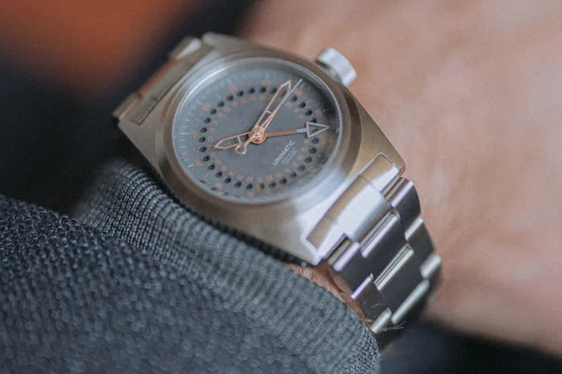 Gros plan d'une montre-bracelet en métal argenté avec cadran sombre.