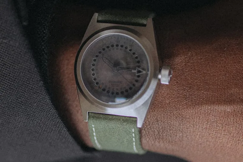 Montre sur poignet avec bracelet vert et boîtier métallique.