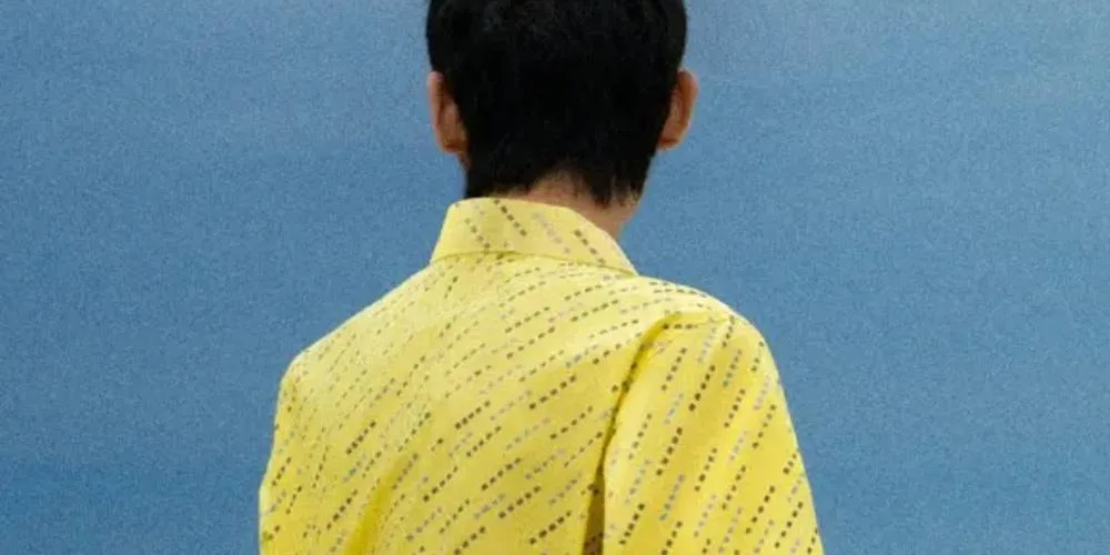 Personne de dos en chemise jaune sur fond bleu
