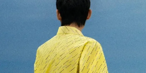 Personne de dos en chemise jaune sur fond bleu