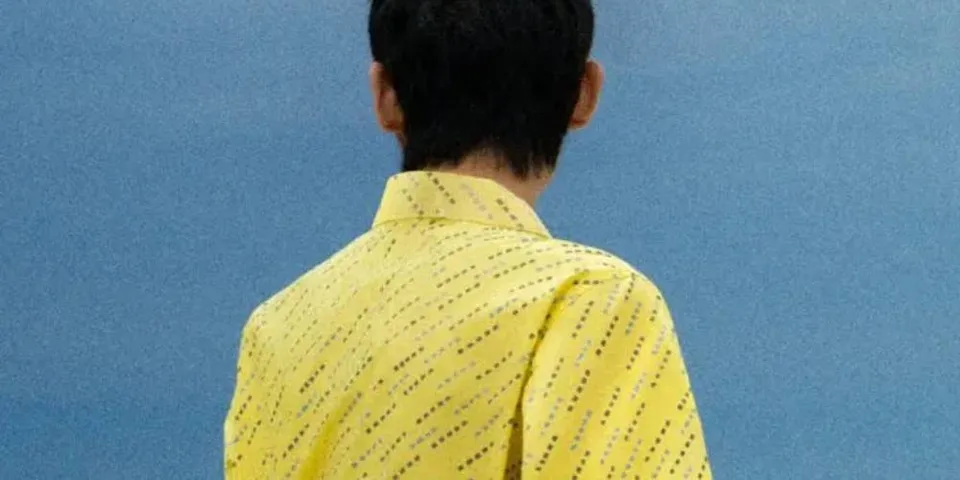 Personne de dos en chemise jaune sur fond bleu