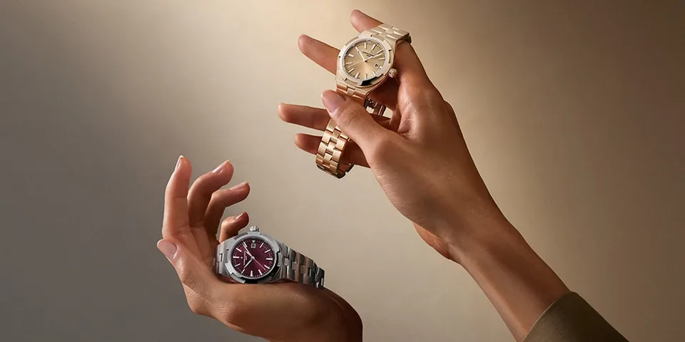 Deux montres au poignet, en métal doré et argenté, sur fond beige.