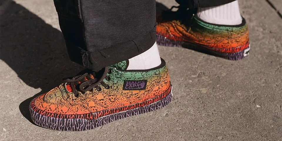 Gros plan sur des baskets colorées aux motifs graphiques, portées avec un pantalon noir.