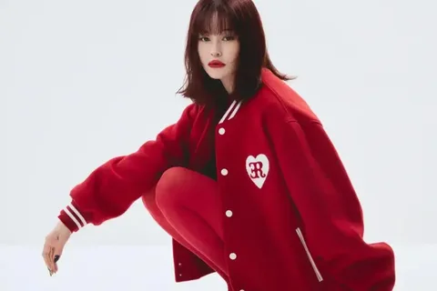 Personne portant une veste rouge posant accroupie sur fond blanc.