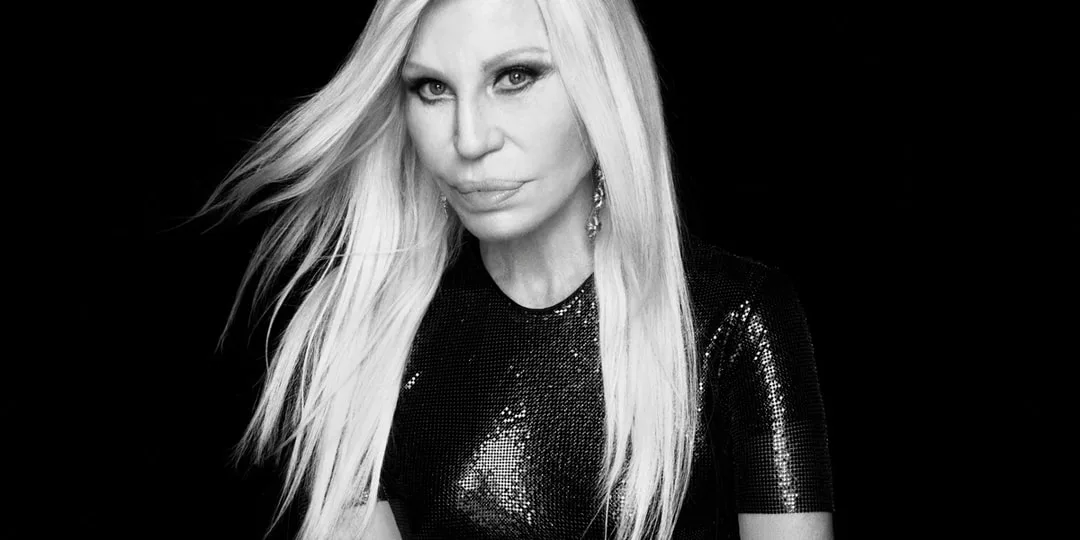 Femme blonde en noir, fond sombre, air sérieux