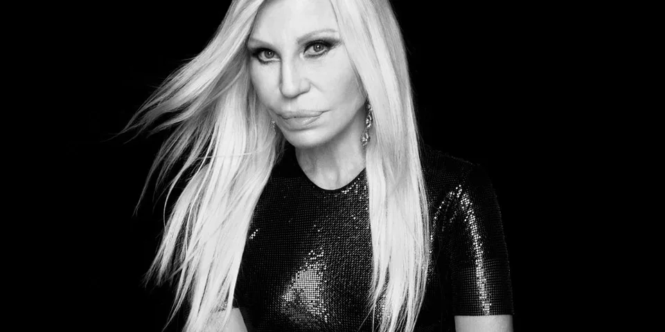 Femme blonde en noir, fond sombre, air sérieux