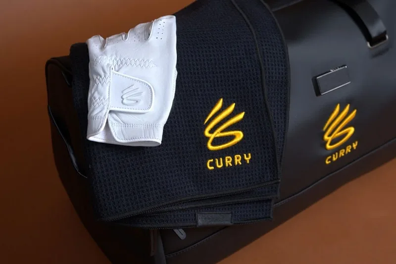 Sac noir avec logo Curry, gants blancs posés dessus.