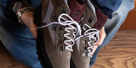 Personne tenant des bottes de randonnée brunes avec lacets blancs.