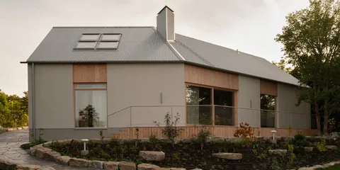 Maison moderne avec toit en métal et grands panneaux vitrés.