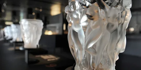 Sculptures en verre représentant des figures humaines dans une galerie.