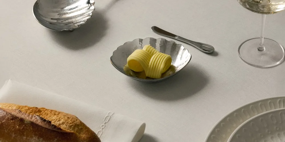 Table dressée avec beurre, pain et verre de vin.