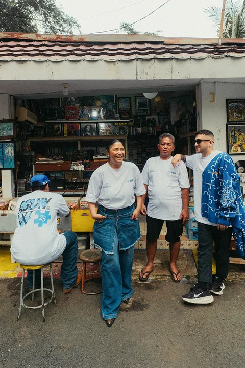 Quatre personnes devant un petit magasin, discutant et souriant.