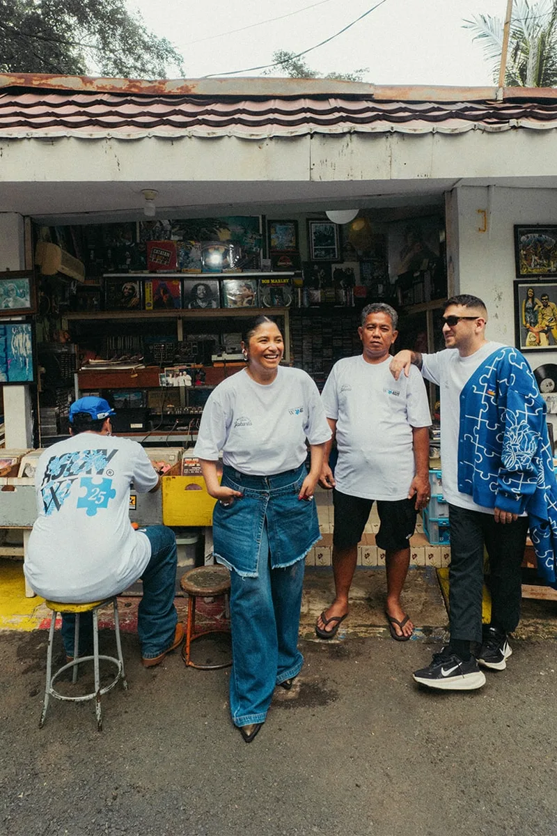 Quatre personnes devant un petit magasin, discutant et souriant.