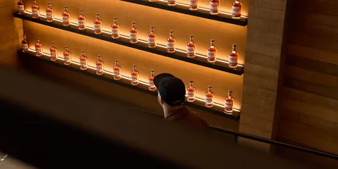 Homme regardant des bouteilles alignées sur des étagères éclairées