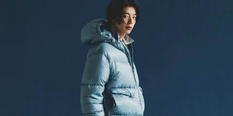 Personne portant une doudoune bleu clair, fond bleu foncé.