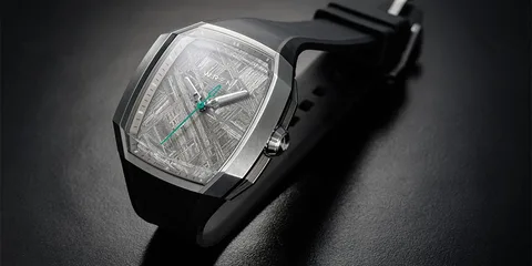 Montre moderne avec bracelet noir et cadran argenté, aiguilles vertes.