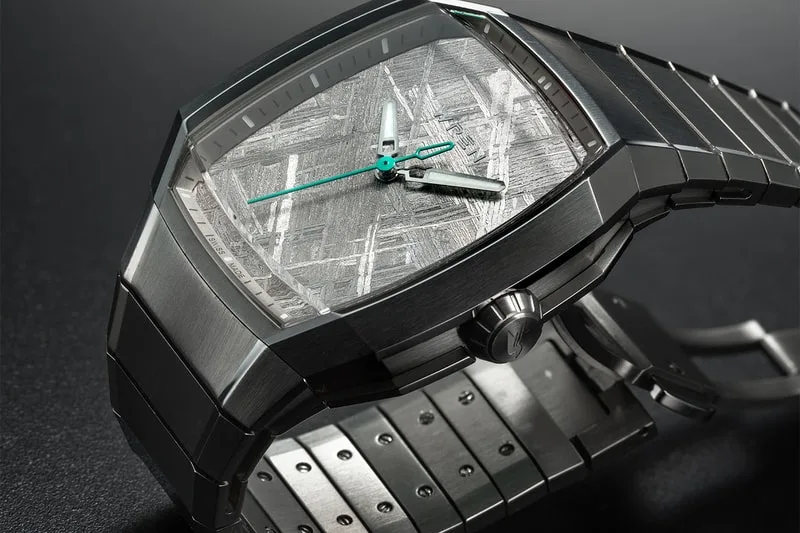 Montre en métal avec cadran texturé et aiguilles vertes.