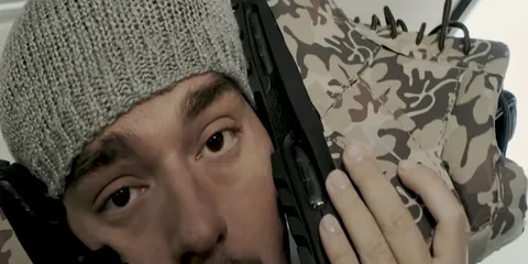 Homme portant un bonnet gris avec des chaussures camouflage.