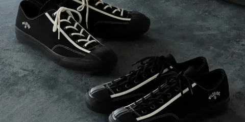 Deux paires de baskets noires sur le sol sombre.
