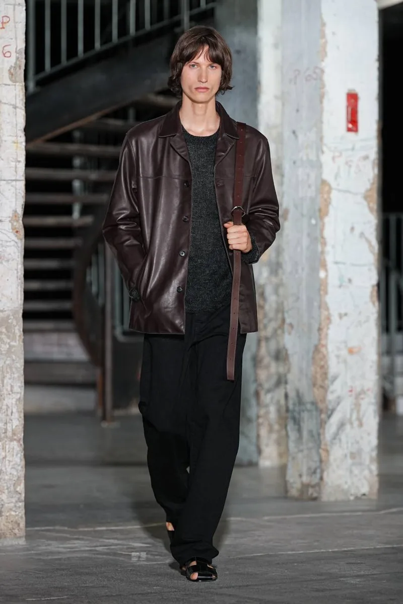 Homme avec manteau en cuir marron, intérieur industriel