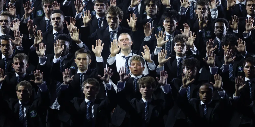 Groupe d'hommes en costume levant les mains lors d'un événement.