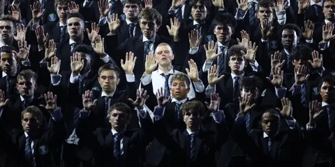 Groupe d'hommes en costume levant les mains lors d'un événement.