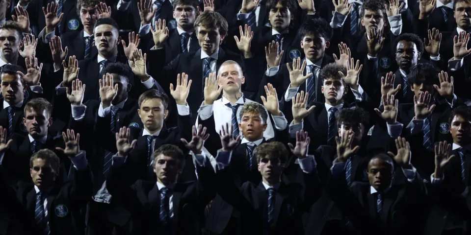 Groupe d'hommes en costume levant les mains lors d'un événement.
