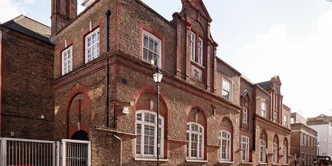 Bâtiment en brique d'époque avec grandes fenêtres et cheminées.
