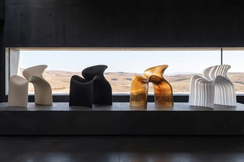 Cinq chaises design devant une fenêtre avec vue sur le désert.