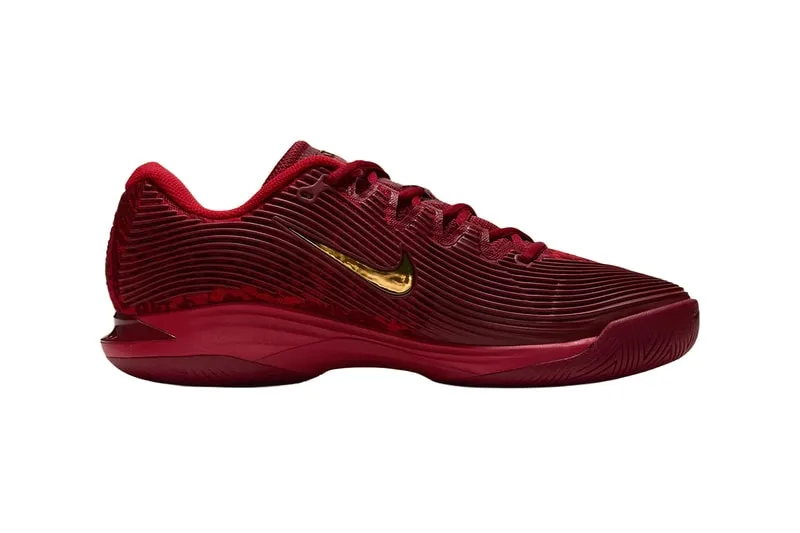 Chaussure rouge avec logo doré sur le côté, vue latérale.