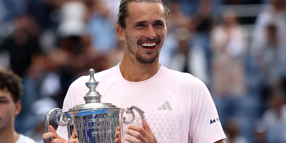 Homme souriant tenant un trophée de tennis sur un court.